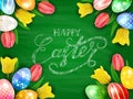 Eggs with tulips and Happy Easter on green chalkboard background