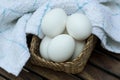 Eggs in a wooden basket with white napkin on wooden table. Royalty Free Stock Photo