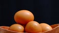 Eggs in a wooden bowl that is neatly and simply arranged which gives an elegant and exclusive impression. Black background.