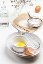 Eggshell, yolk and whisk in ceramic bowl. Flour and sieve on paper. Egg and water bottle Royalty Free Stock Photo