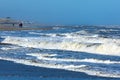 waves in the rough North sea with some people walking along the shore Royalty Free Stock Photo