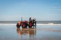 Egmond-aan-Zee, Netherlands - 2016-04-10: 3 men of the organisation with a red tractor on the beach