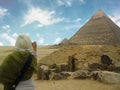 Egypt. Cairo. Giza.The young woman makes a photo of pyramids. She is standing back to the camera. The blue sky with a clouds and s