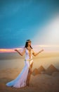 Egypt Woman pagan prays hands raised to heaven blue sky. Sexy girl Egyptian goddess Queen Cleopatra. yellow sand Sahara