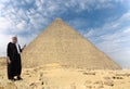 An Egyptian with a turban points a finger at the historic pyramid of Giza. Royalty Free Stock Photo