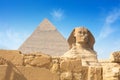 Egyptian Great Sphinx full body portrait with head, feet with all pyramids of Menkaure, Khafre, Khufu in background on a Royalty Free Stock Photo