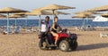 An Egyptian guide and a young girl ride on the beach near the red sea. Tours of the desert on Quad bikes.