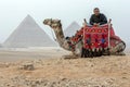 An Egyptian man and his camel in front of the Giza pyramids in Egypt. Royalty Free Stock Photo