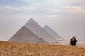 Egyptian man sitting on a hill with the blurred pyramids on the background, Cairo, Egypt