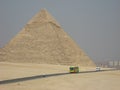 Egyptian pyramid, small figure of man and touristic bus Royalty Free Stock Photo