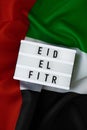 EID EL FITR - Eid Mubarak - Happy Holidays text frame on United Arab Emirates waving flag made from silk material Royalty Free Stock Photo