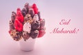 Eid Mubarak greeting card with red lettering; A bundle of edible flowers, arrangement of strawberries covered with chocolate