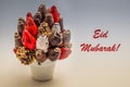 Eid Mubarak greeting card with red lettering; A bundle of edible flowers, arrangement of strawberries covered with chocolate