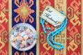 Eid mubarak text on the card with blue rosary and turkish delight