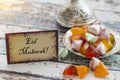 Eid mubarak text on greeting card on vintage table with candies