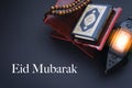 EID MUBARAK text with Holy Al Quran with written arabic calligraphy meaning of Al Quran, lantern lamp and rosary beads or tasbih o Royalty Free Stock Photo