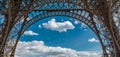 Eiffel tower closeup arch frame over blue cloudy sky in Paris France