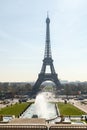 The Eiffel tower in daylight blue sky with some cloud. Champ de Mars park and people in foreground