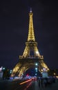 The Eiffel Tower shining with evening lights and stripes of car lights on the road