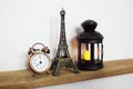 Eiffel tower statue, alarm clock and black lantern Home decoration accessories on wooden shelves Royalty Free Stock Photo