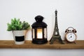 Eiffel tower statue and black lantern with LED candle light and alarm clock on wooden shelves Royalty Free Stock Photo