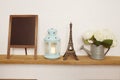 Eiffel tower statue, blue lantern, flower in metal vase and empty blackboard for copy on wooden shelves Royalty Free Stock Photo