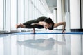 Eight-Angle Pose. Woman yoga practice pose training concept in gym hall with big windows