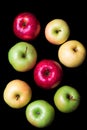 Eight red, green and yellow apples with water drops on black background