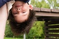 Eight-year-old boy hangs upside down from a bench at his mother`s legs. Funny picture about of children`s pranks