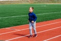 Eight-year-old Caucasian boy in red sneakers runs through a sports stadium