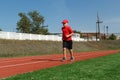 An eight-year-old child in a red cap and t-shirt runs on the red carpet at the track and field stadium