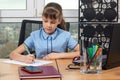 An eight-year-old girl at an office table is writing an important document