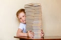 An eight-year-old smiling child looks out from behind a large stack of books. children and reading Royalty Free Stock Photo