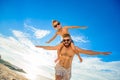 Eight years old boy sitting on dad`s shoulders. Both in swimming shorts and sunglasses, having fun on the beach. Bottom view