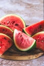 Eighths of a watermelon on a wooden plate on beige structured background Royalty Free Stock Photo