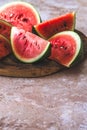 Eighths of a watermelon on a wooden plate on beige structured background Royalty Free Stock Photo