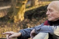 An eighty-year-old man walks in a public park, pointing somewhere with his hand