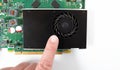 A finger points to the dust in the fan of the graphics card
