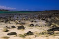 El Cotillo, North Fuerteventura: View over bright scattered stoneson beach in shallow water on turquoise lagoon of beach La Concha Royalty Free Stock Photo