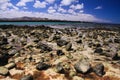 El Cotillo, North Fuerteventura: View over bright scattered stoneson beach in shallow water on turquoise lagoon of beach La Concha Royalty Free Stock Photo