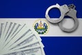 El Salvador flag with handcuffs and a bundle of dollars. The concept of illegal banking operations in US currency