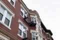 Elaborate architectural details on windows, overhangs, and top edge of a classic urban apartment building, metal balconies