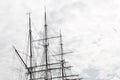Elaborate rigging on a three mast tall ship against a gray sky