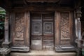 A elaborately carved wooden door of a traditional stilt house. Portray the historic architecture and cultural heritage of