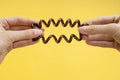 Elastic band spring for hair in hands, brown on a yellow background