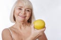 Elated senior woman having an apple in her hand