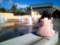 A girl sitting on a street stone bench and watching attentively many water fountains