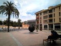 A people couple sitting on a bench and a landscape with palm trees of the center of Elche city