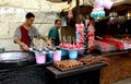 Two handicraftsmen of candies, sugar cotton and caramelized apples at their street stall.