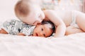 elder brother blonde hair kiss baby sister lying on bed